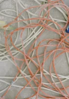 Kabel Entsorgen - schmutzige weisse und orange Kabel liegen am Boden